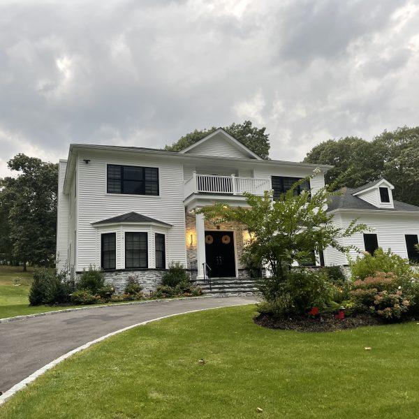 A white house with a meticulously maintained driveway and lush grass in Long Island.