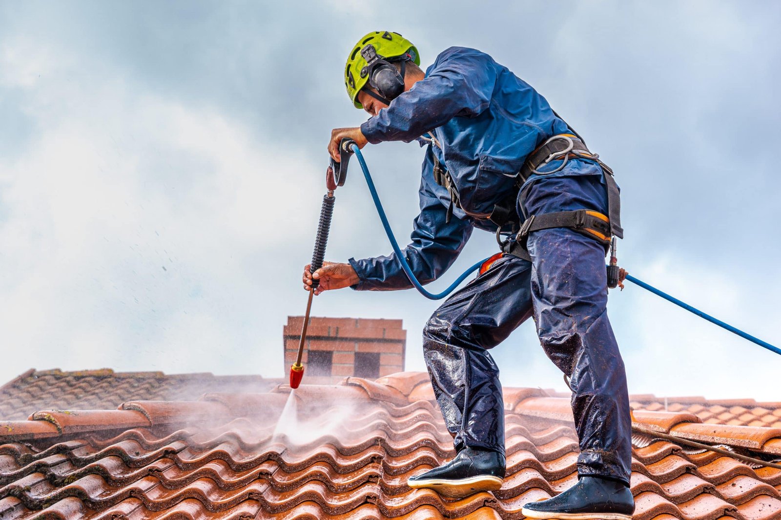 A man is using a pressure washer to clean a roof.