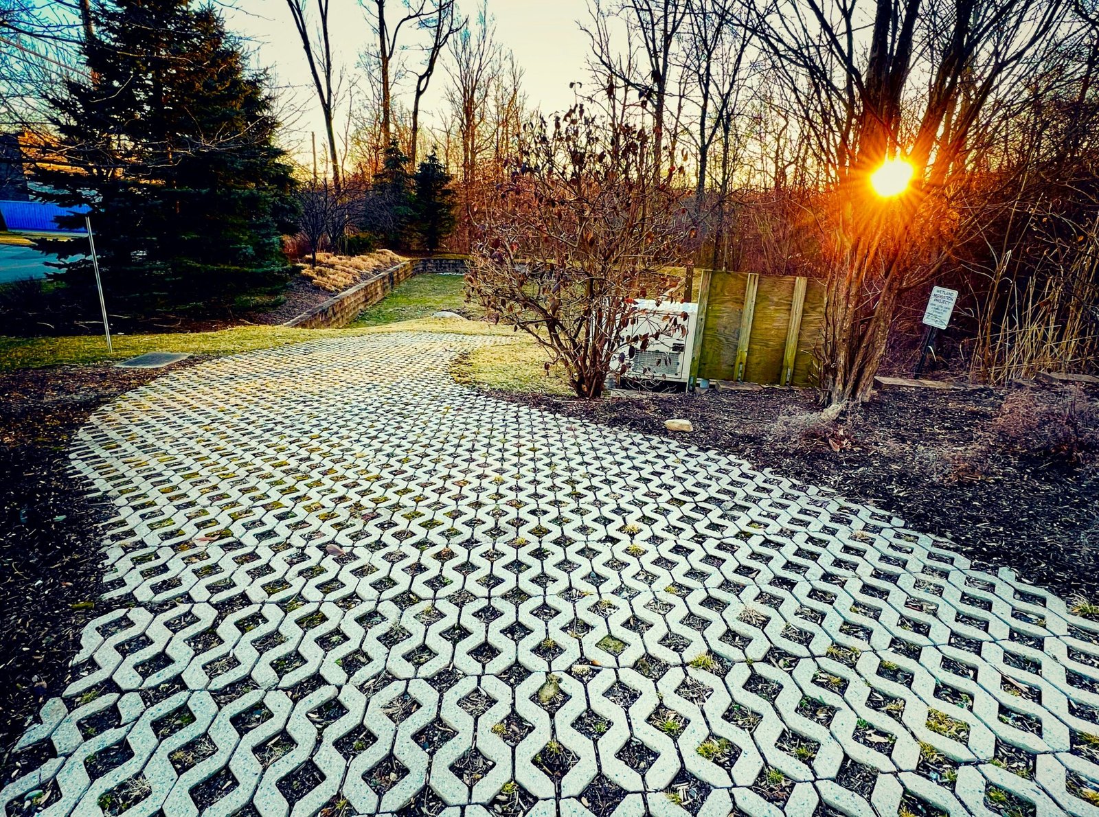 Winding honeycomb permeable paver driveway path lit by evening sunset light