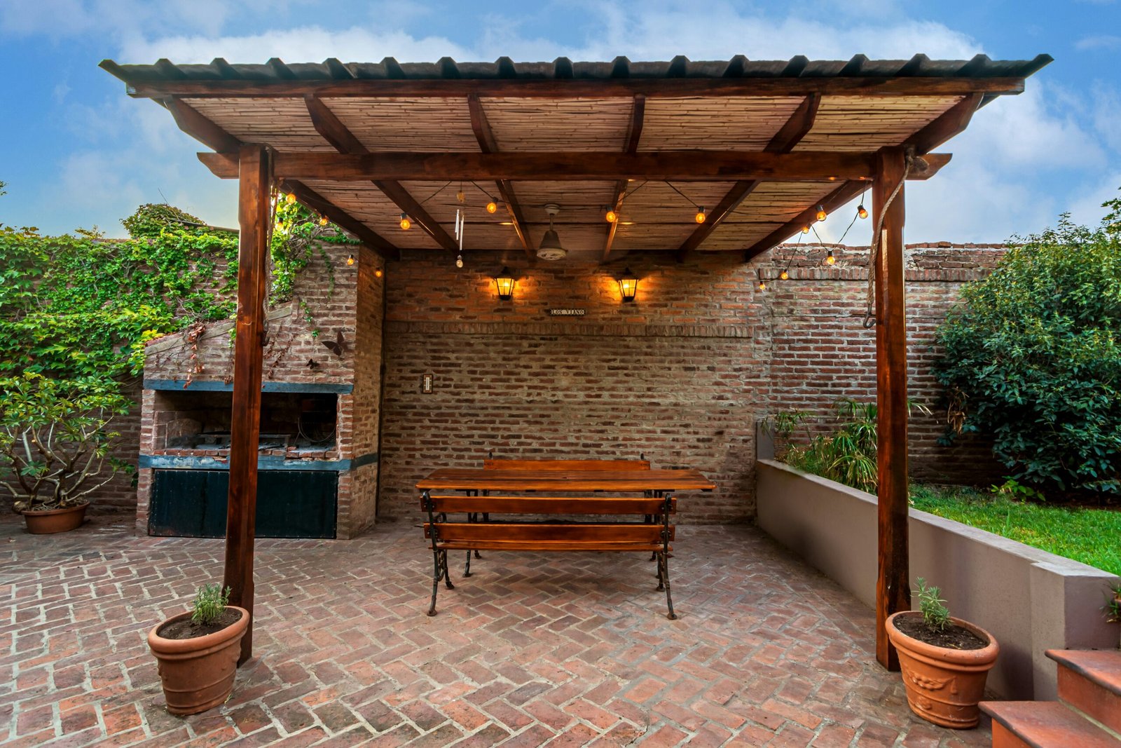 Herringbone brick paver patio with a wooden pergola overhead, courtyard style