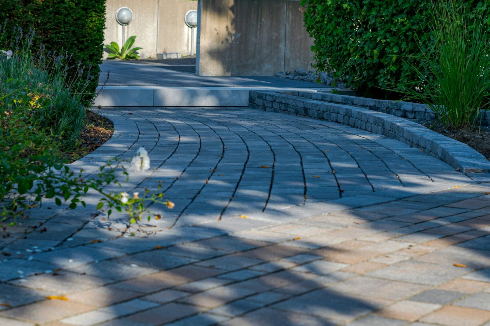 Curved paver walkway running alongside a matching natural stone retaining wall