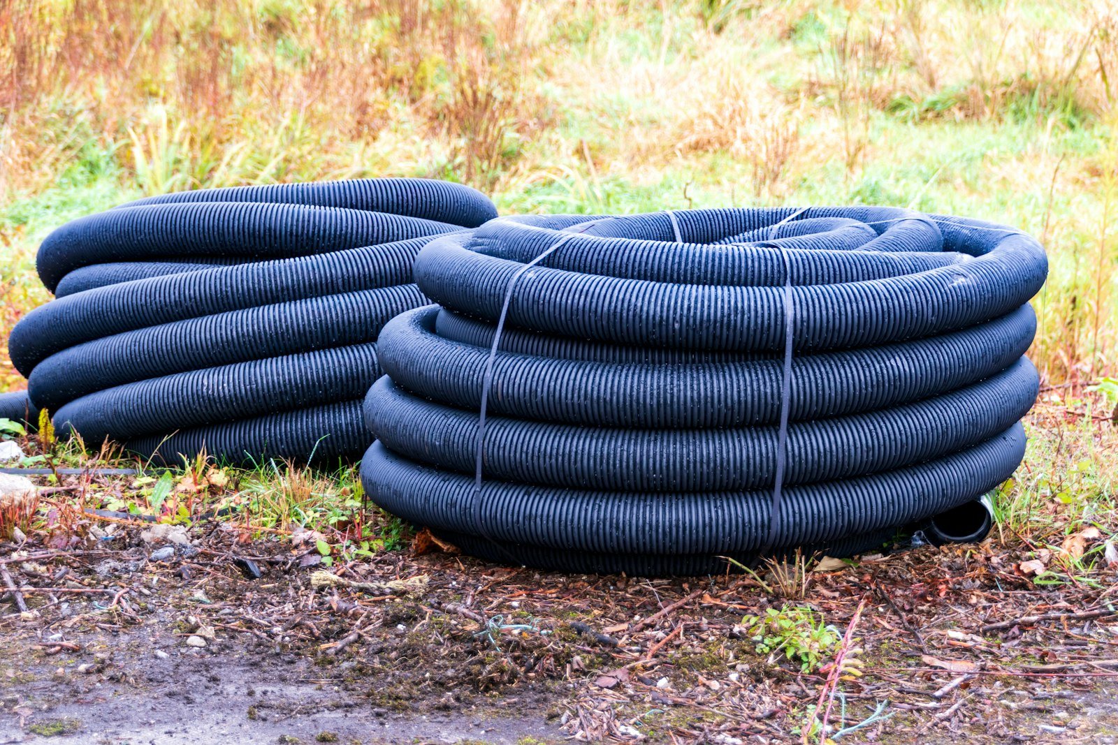 Coils of black corrugated drainage pipe on site before installation