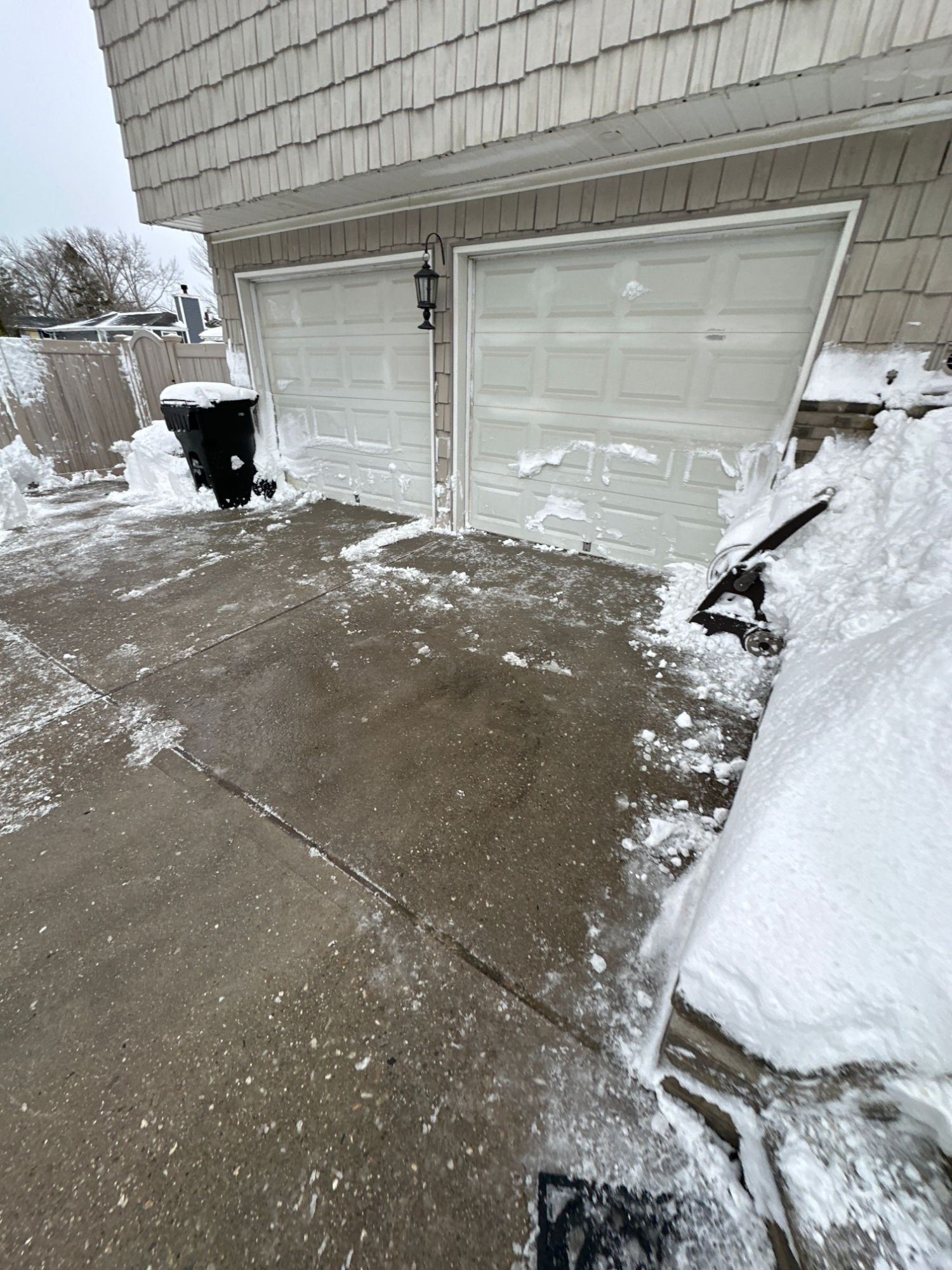 Concrete apron in front of a two-car garage cleared down to the surface after snowfall
